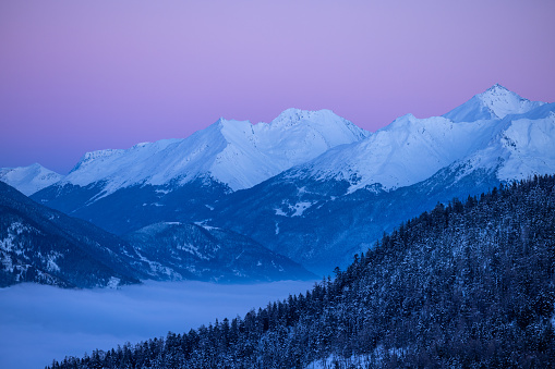 peaks of a snow-capped mountain range at dusk with a beautiful pink sky