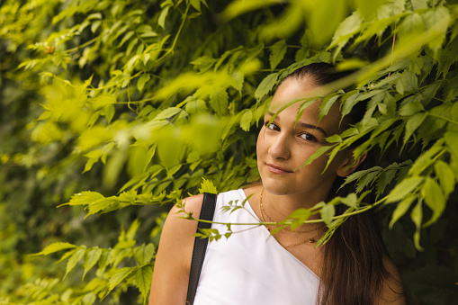 Portrait photos of attractive woman. Blurry leaves in front of the lens.