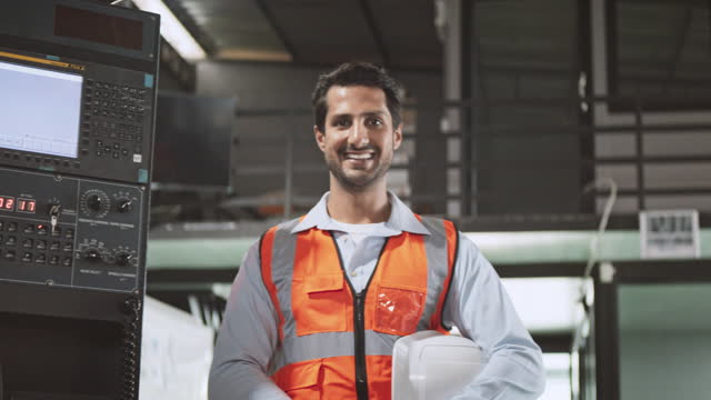 Portrait of young adult Caucasian white male engineer factory worker smiling with confidence, holding hardhat. Engineering industry business, industrial job career, people at work concept. Slow motion