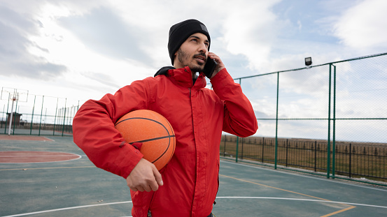 Young man talking on the phone on the basketball court