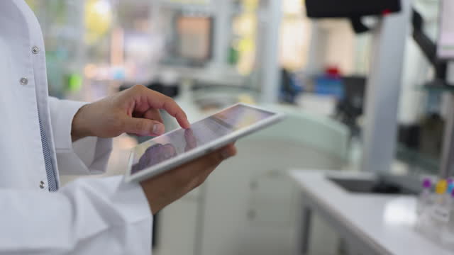 Close-up of a scientist using a digital tablet looking at the results of some blood samples