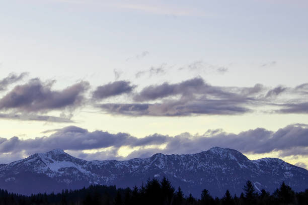 Full frame image of mountain range while sunset in autumn with some clouds and autumn leaf coloured trees.
