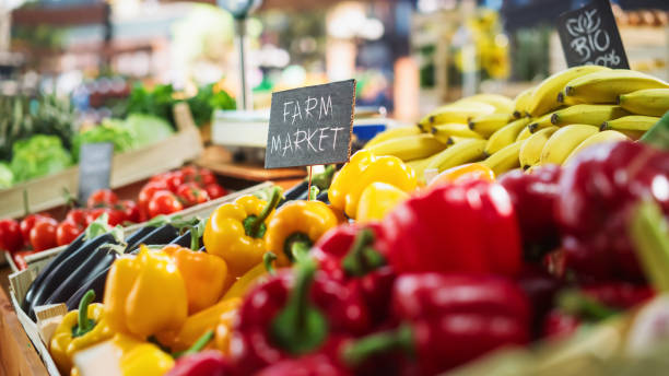 farmers market food stall with a selection of ecological fruits and vegetables. organic red and yellow bell peppers, eggplants, natural chemical-free bananas and other groceries on the outdoors stand - green bell pepper bell pepper red bell pepper groceries stock-fotos und bilder