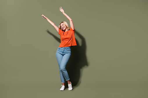 Full body photo of attractive young woman dancing performance disco dressed stylish orange clothes isolated on khaki color background.