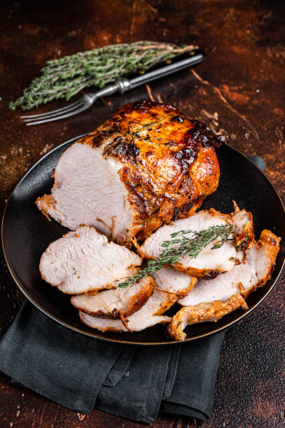 istock Roast rolled pork ham meat on plate with thyme. Dark background. Top view 1934747796