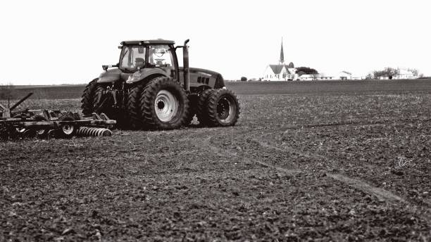 istock Tractor in Bare Dirt Field with Church on Horizon 1934756530