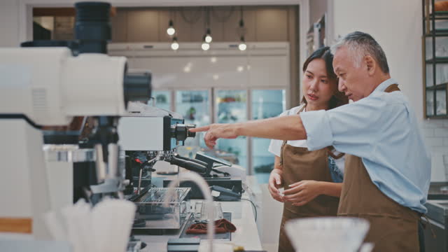 Senior Business Owner teaching a new employee in his coffee shop