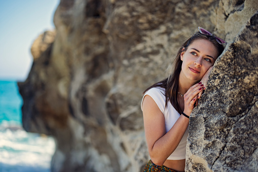 Teenage girl is enjoying spring day in Calabrian town of Tropea. She is leaning on the rock formation on the beach. Springtime, off-season vacations day in Catania, Italy.
Shot with Canon R5