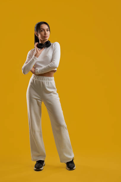 istock Trendy woman wearing white jumper, using wireless headphones in studio. 1934813406