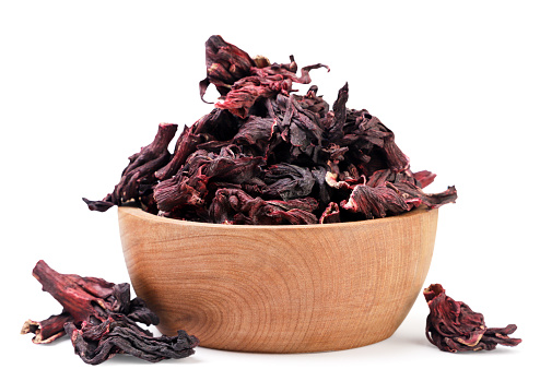 Hibiscus tea leaves in a wooden plate and scattered close-up on a white background. Isolated