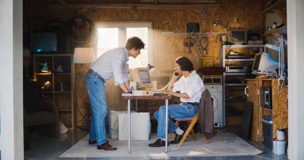 istock Two Caucasian Male Stock Traders Working In Retro Garage, Using Old Computer With Candlestick Chart And Landline Phone To Pitch A Public Company To Investors. Partners Celebrating Successful Sale. 1934834785