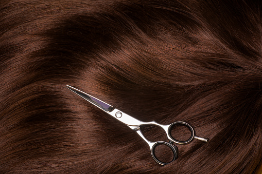 A brown female wig with scissors