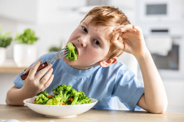 istock A little boy is having lunch and eating broccoli. 1934846022