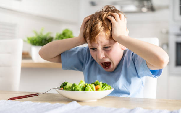 istock Shocked and upset little boy because he has to eat broccoli for dinner, which he doesn't like. 1934846555