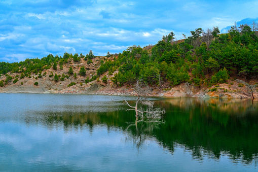 A landscape photo of forest and reflections on water by the lake in Usak