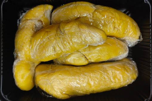 Close-up directly above shot of Musang king durian of Malaysia -  Mao Shan Wang covered in plastic wrap for takeaway. Concept : unsustainable plastic packaging on fruits