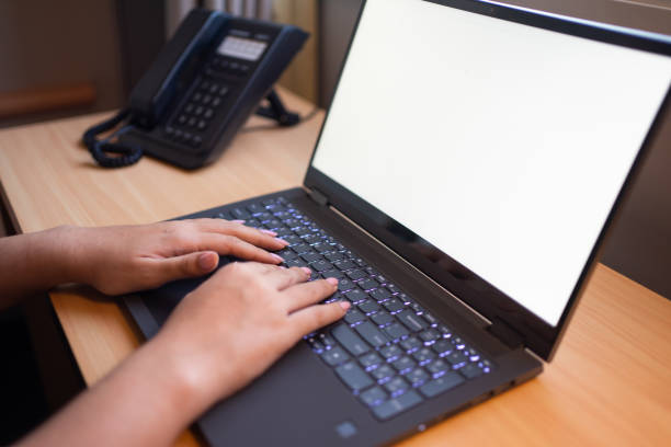 istock Close-up of a girl's hands using her computer. Blank screen mock-up. 1934856525