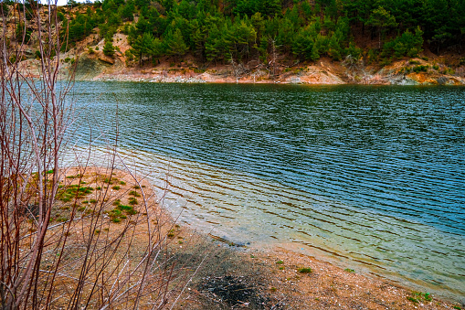 A landscape photo of forest and reflections on water by the lake in Usak