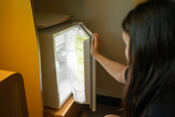 istock A girl opening a small hotel refrigerator with white light. 1934857739
