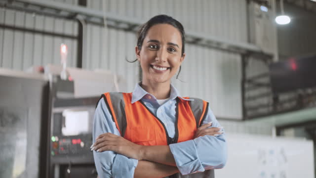 Portrait of young adult Caucasian white female engineer factory worker smiling, arms crossed with confidence. Engineering industry business, industrial job career, people at work concept. Slow motion