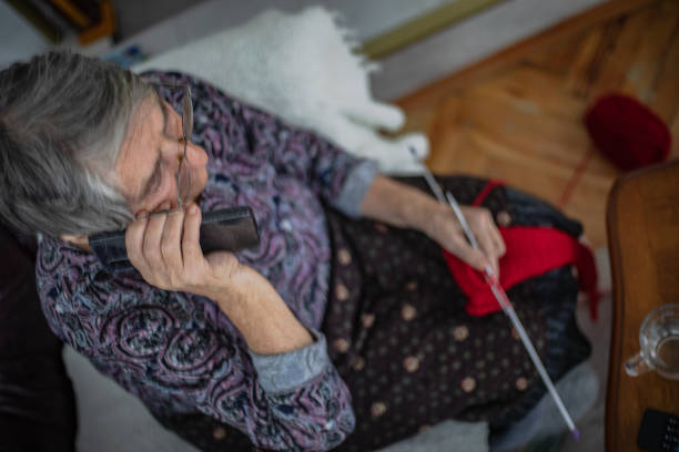 Knitting fabric with needles, elderly woman