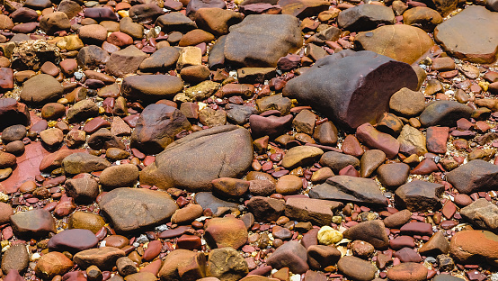 Pink stone texture and background. Close up of wet decorative stones. The Pink Coast or Lan Him Chomphu with sea background at Chanthaburi in Thailand