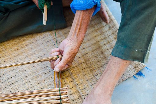 Close-up of Thai senior man  doing craft work with bamboo in rural village