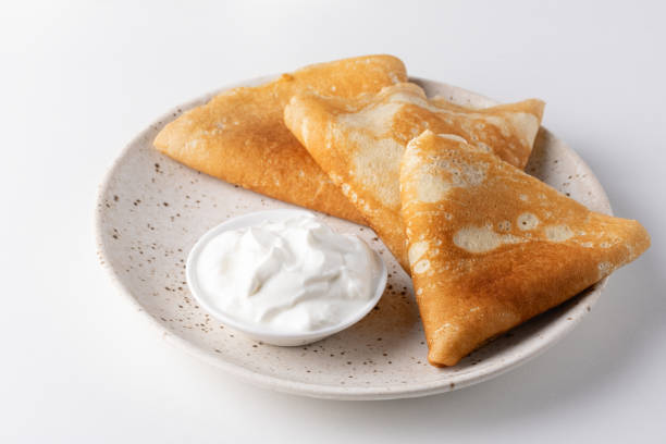 Stack of russian thin pancakes blini with fresh sour cream