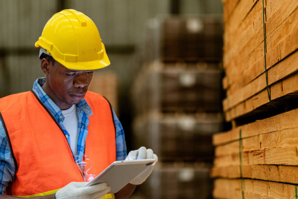 istock African worker carpenter wearing safety uniform and hard hat working and checking the quality of wooden products at workshop manufacturing. man and woman workers wood in dark warehouse industry. 1934941141
