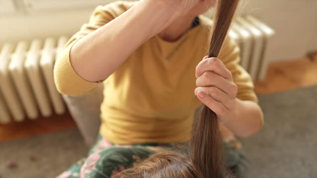Mother doing head lice cleaning on daughter at home