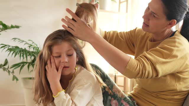 Mother doing head lice cleaning on daughter at home