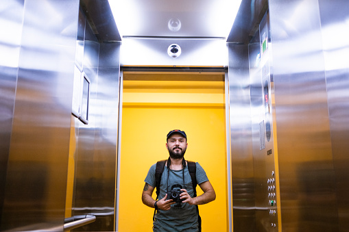 A photographer takes an elevator selfie in the mirror