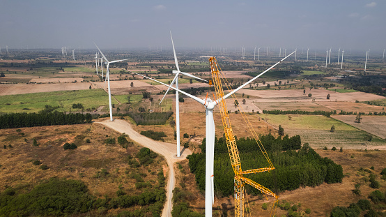 The blade of the wind turbine operates by  crane to install the engine of a wind turbine tower to generate green energy and reduce global warming and climate change