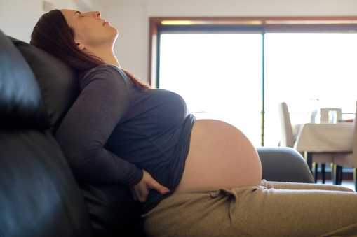 Pregnant woman on sofa with back pain