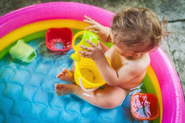 baby boy sitting in a pool at the garden and playing with water toys - swimming pool one baby boy only toddler image type стоковые фото и изображения