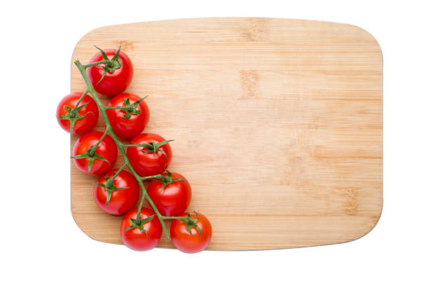 Fresh cherry tomatoes on a wooden cutting board isolated on white background.