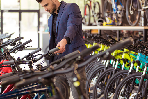 Young businessman watching bicycles in bicycle shop.