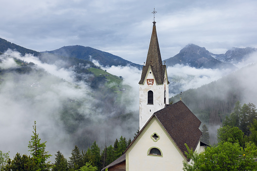 Church on the background of the Italian Alps in the morning clouds