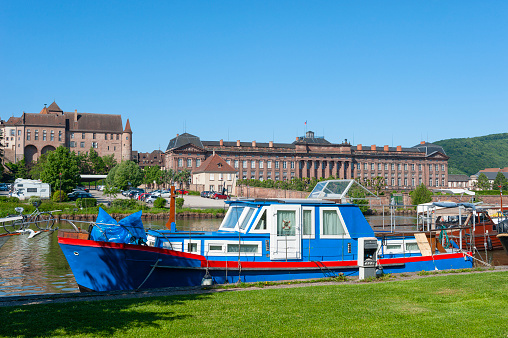 Saverne, France - May 26, 2022: Houseboat on Rhine-Marne Canal in Saverne. In background Old Episcopal Castle and Rohan Castle. Department Bas-Rhin in the Alsace region of France