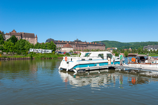 Saverne, France - May 26, 2022: Houseboat on Rhine-Marne Canal in Saverne. In background Old Episcopal Castle and Rohan Castle. Department Bas-Rhin in the Alsace region of France