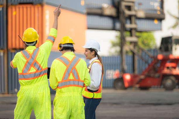 istock Group of workers in the import and export industry use walkie talkies to communicate with drivers of reach stacker containers in an empty container warehouse. 1935045071