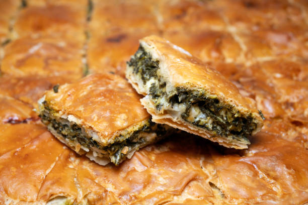 two pieces of spinach pie two pieces of spanakopita (spinach pie) on whole pie spanakopita stock pictures, royalty-free photos & images
