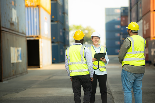 Group of engineers working with laptop in the container yard. This is a freight transportation and distribution warehouse.