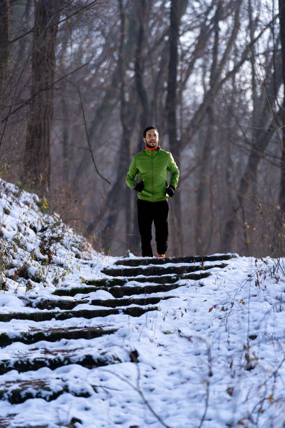 Athlete man running at snow in the nature.