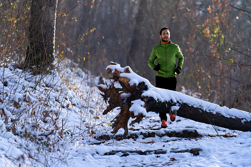 Athlete man running at snow in the nature.