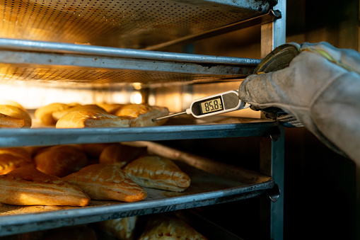 Close-up on a baker checking the temprature of some pastries baking in the oven - food concepts