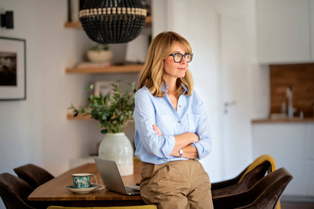 istock Attractive mid aged woman deep in thought and standing in a modern home 1935071429