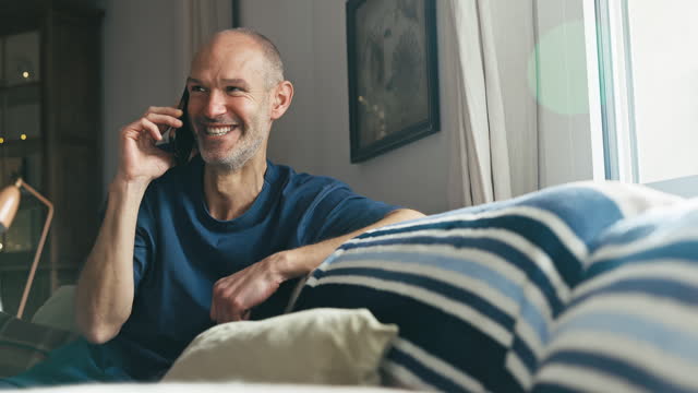 Mature man relaxing at home and enjoying phone call