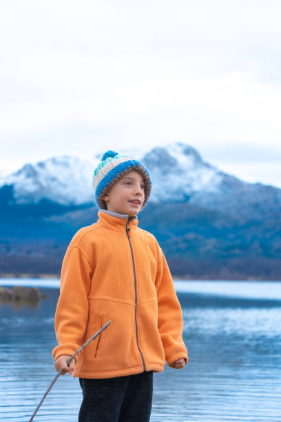 Boy in winter outdoors with woolen hat with snowy mountains behind