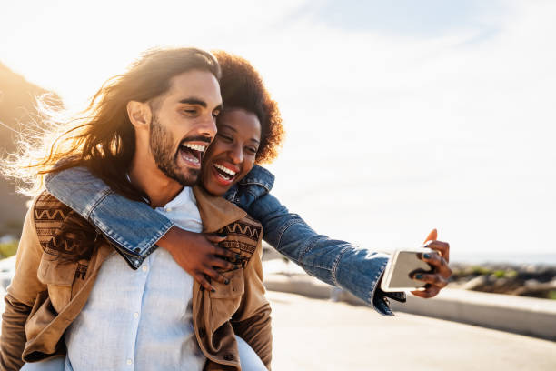 istock Happy multiracial couple having fun taking selfie with mobile smartphone during vacations - Youth people love and social relationship concept 1935106175